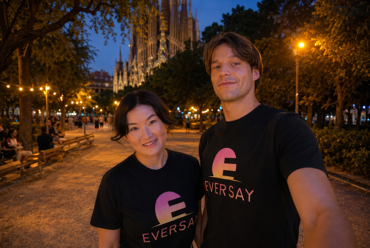 Rikke and Aljosha standing together in matching black Eversay t-shirts in a Barcelona park at blue hour, Sagrada Família behind them